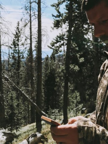 A man looking at gps during a colorado elk hunt wearing First Lite hunting apparel