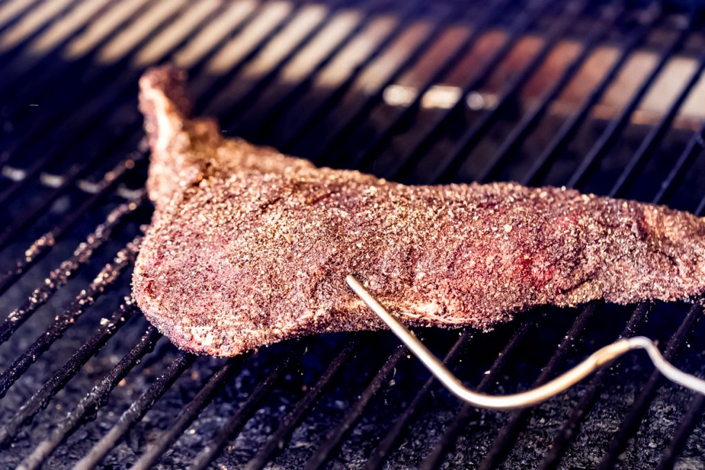 an elk tri-tip roast on a smoker with a temperature probe in it