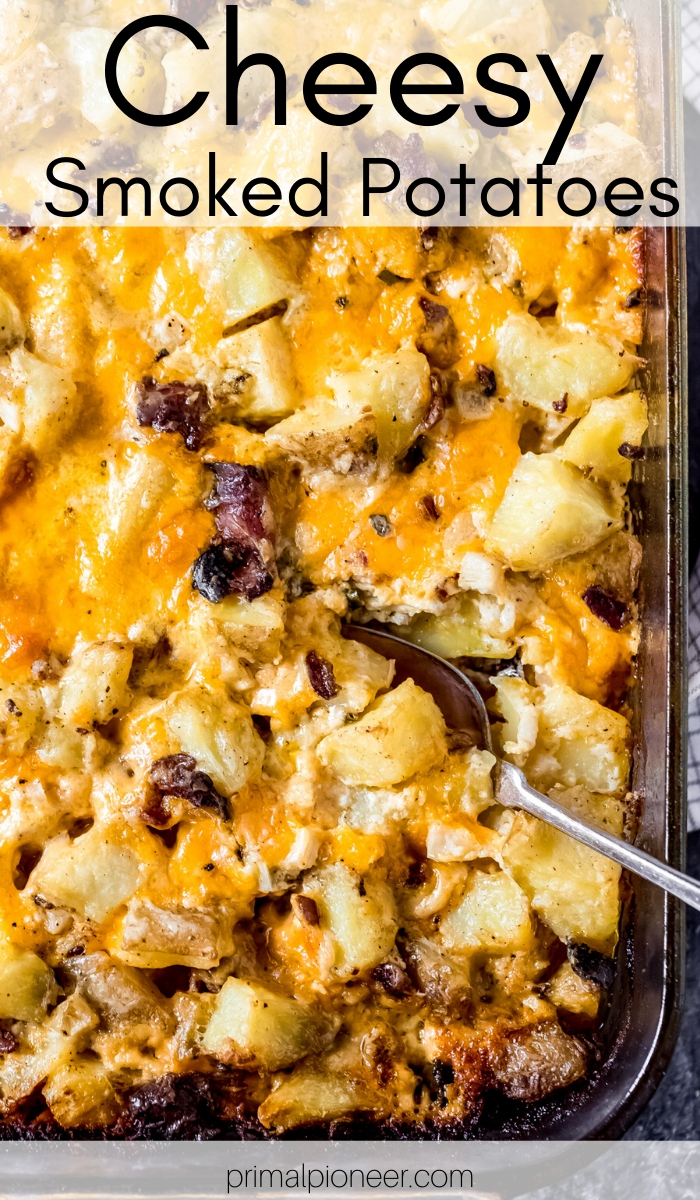 a 9x13 baking dish of cheesy smoked potatoes with a spoon in it