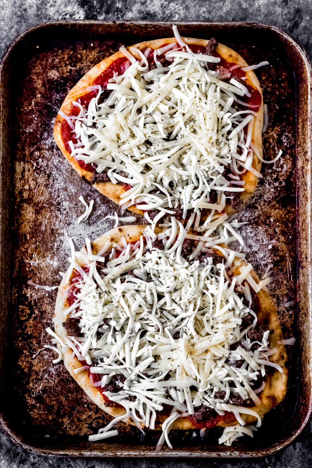 two uncooked venison pizzas on a baking sheet