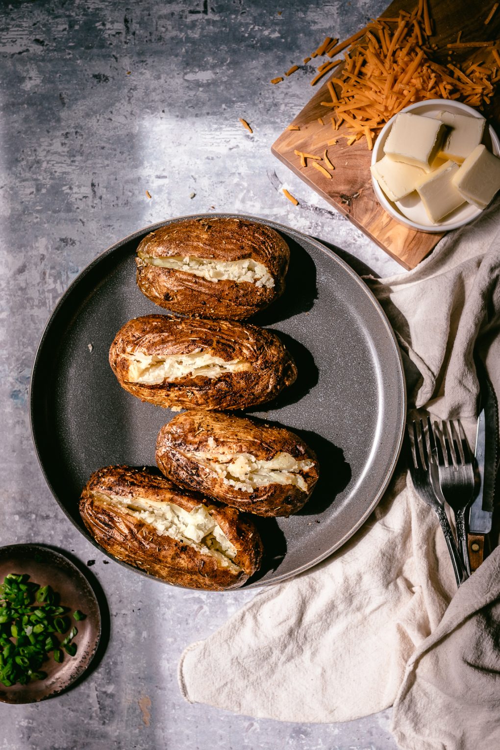 four baked potatoes on a plate