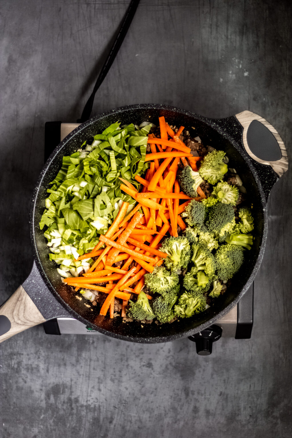 vegetables in a skillet including broccoli, carrots, and green onions