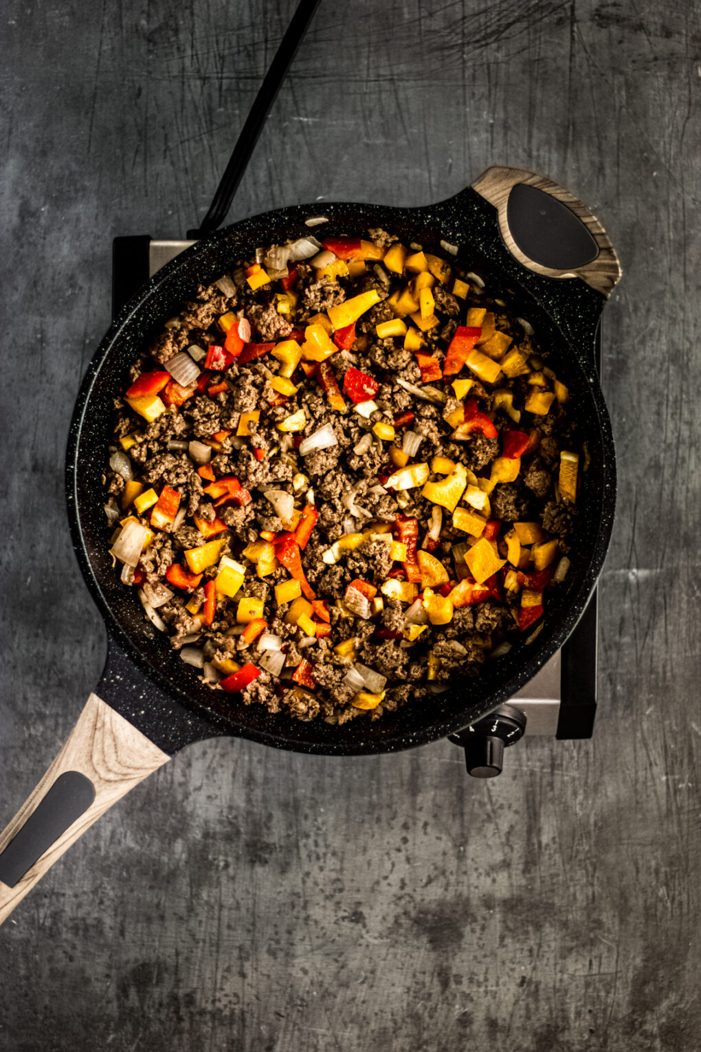combining meat and bell peppers into a skillet