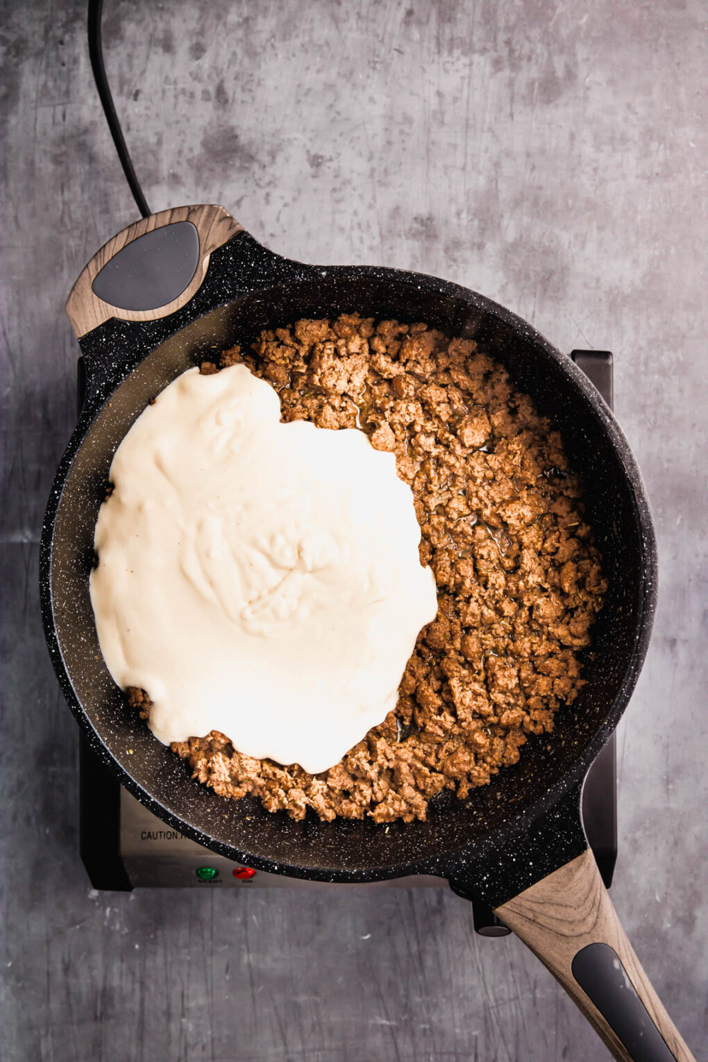 cooked ground venison in a skillet with alfredo sauce
