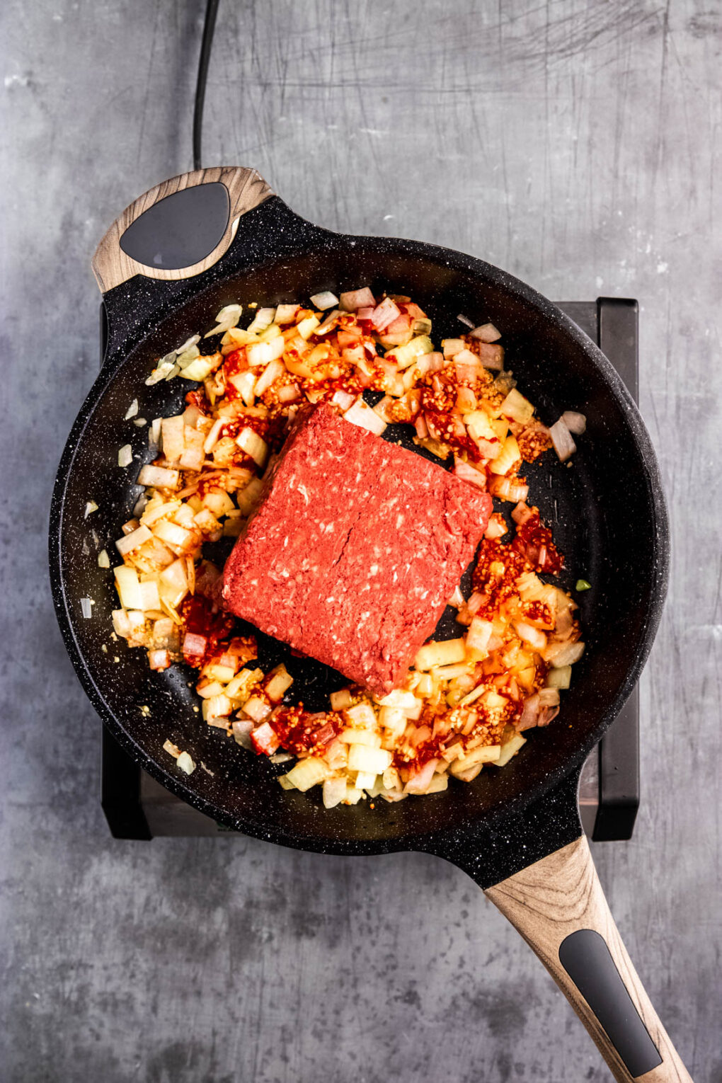 Meat in skillet with onions and tomatoes