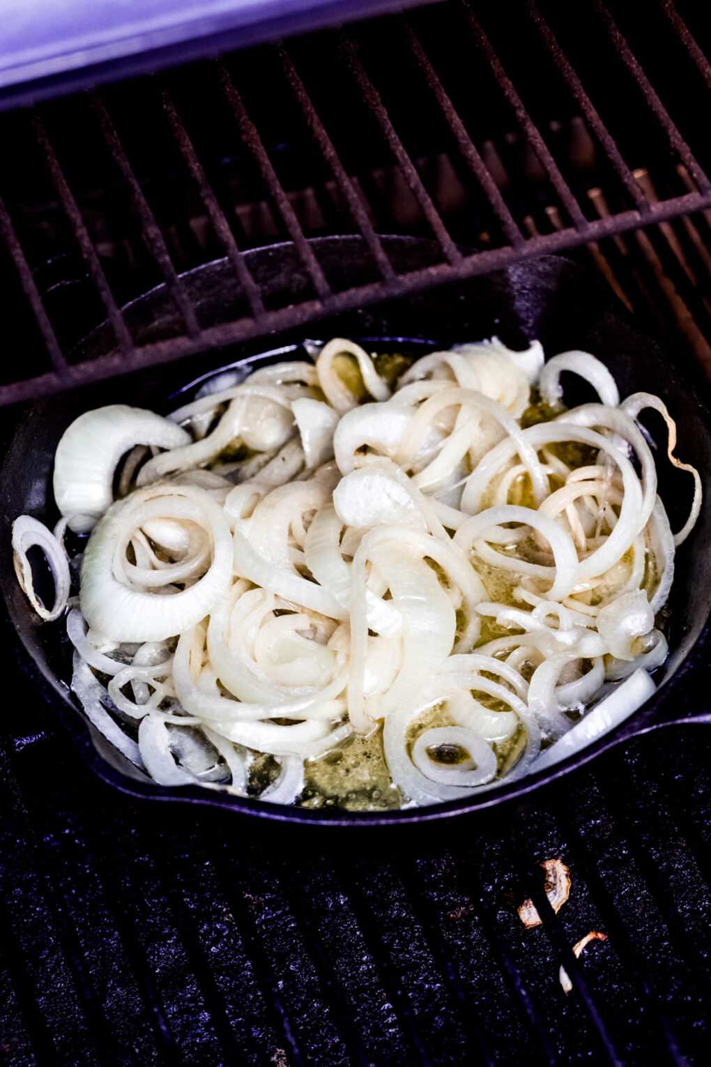 onions in a cast iron skillet on a Traeger grill